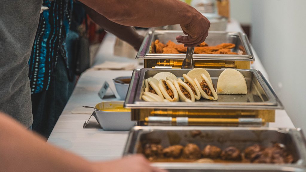 People use tongs to pick up food from trays.