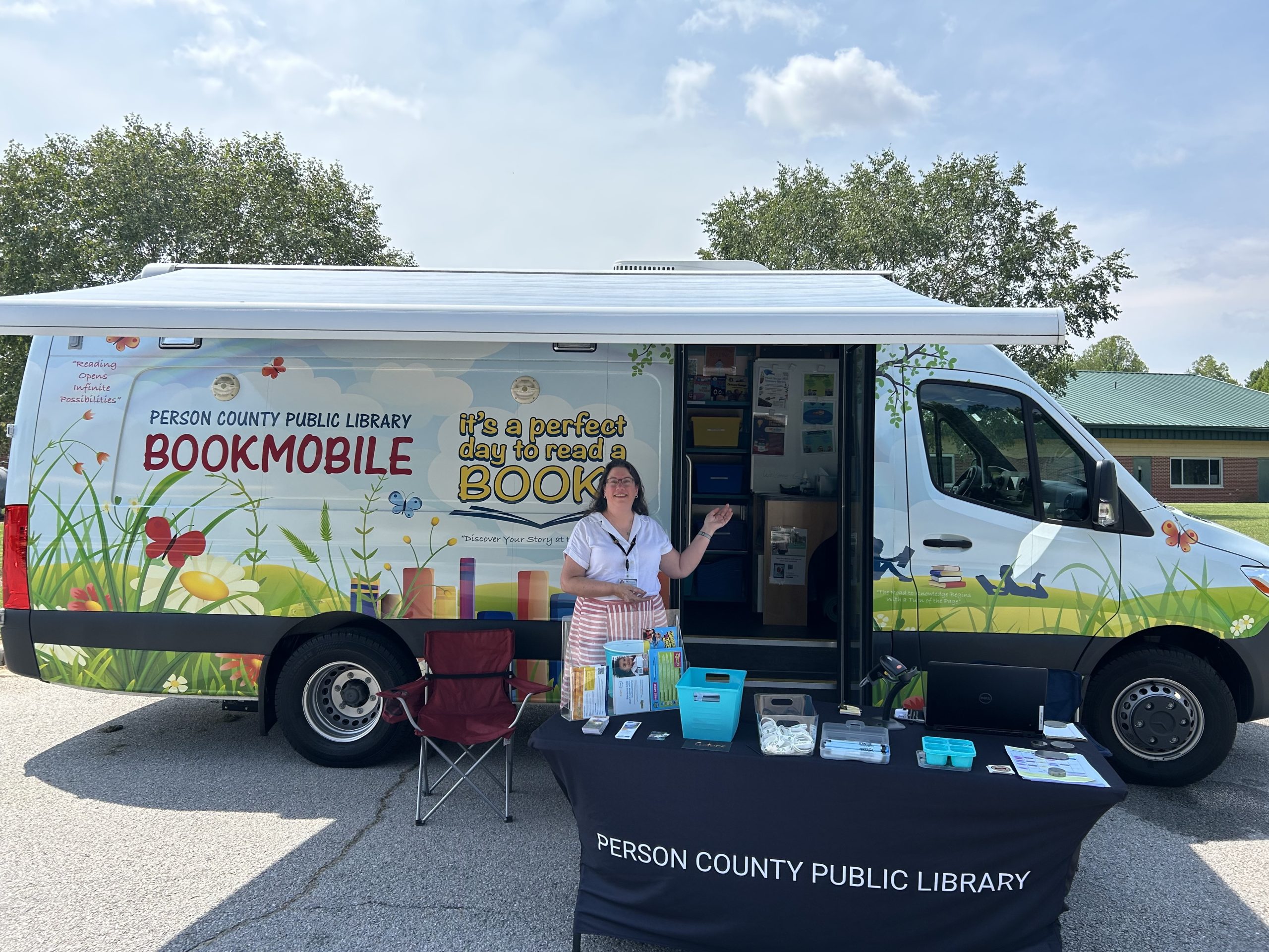 a woman stands in front of a book mobile