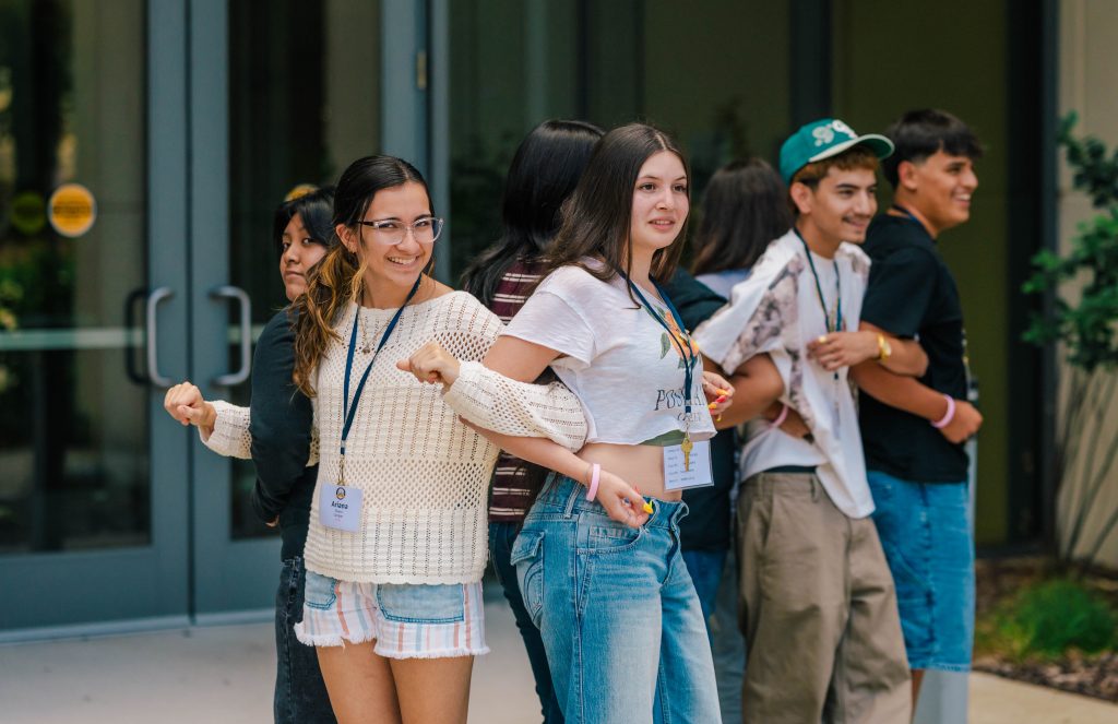 Students lock arms as outside of a campus building.
