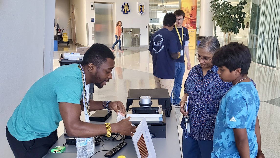A volunteer from UNCG JSNN community outreach program checking in participates for activities.