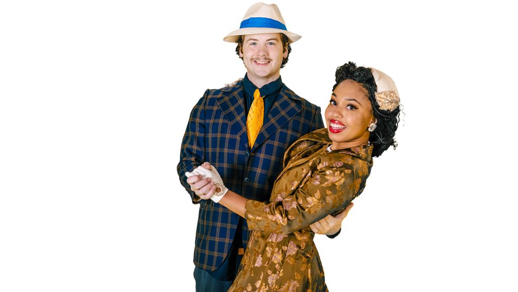 Two actors pose in period 20th century suit and tie and dress.