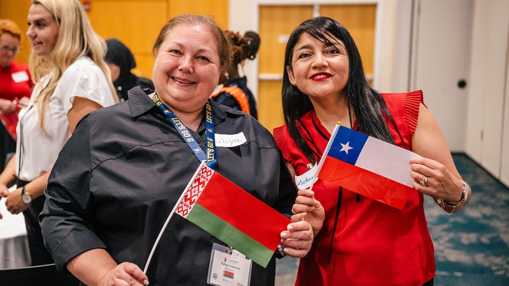 Two women holding flags of different countries.