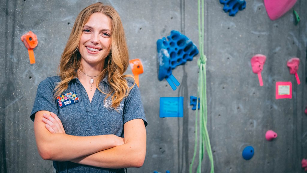 Sylvie Trainor in front of the UNCG climbing wall.