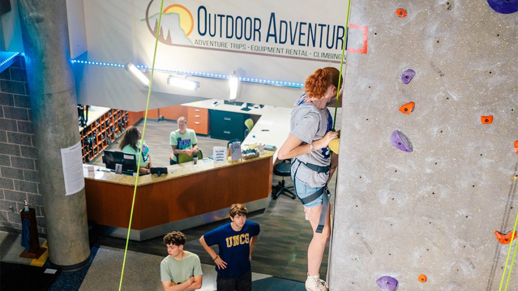 A student climbs an indoor climbing wall.