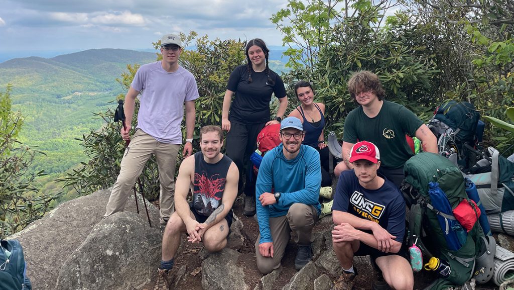 A group of people on a rock with a view of the mountains.