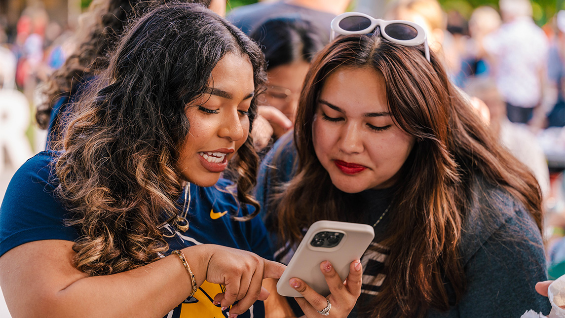 Two women look at a phone.
