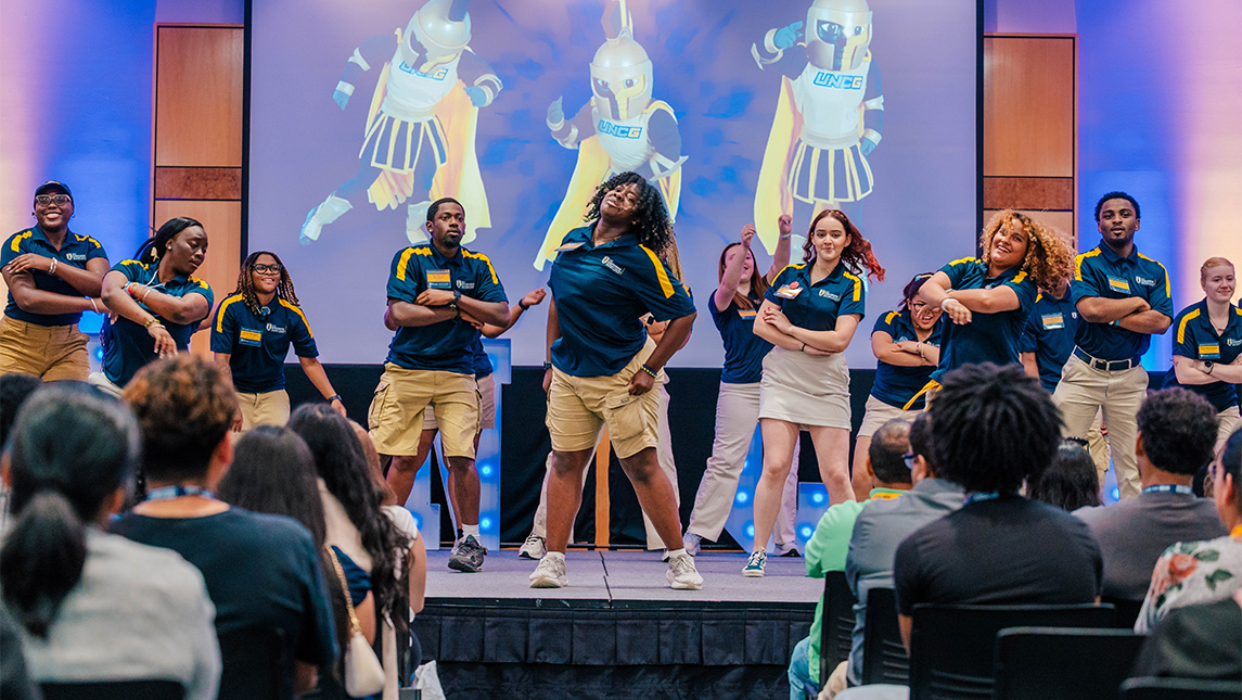 UNCG students dance in matching blue shirts.