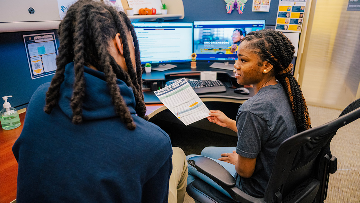 A student and advisor look at a paper together.