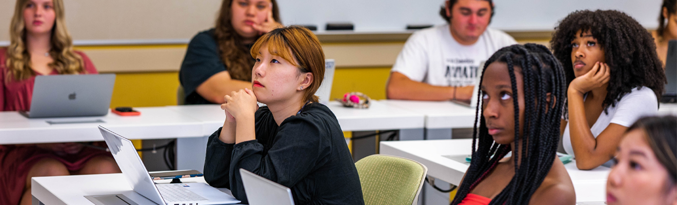 A group of students in a classroom looking towards the front of the room.