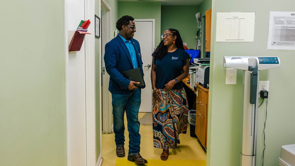 Chauncey Greene and Johnette Walser walk through a doctor office hallway.