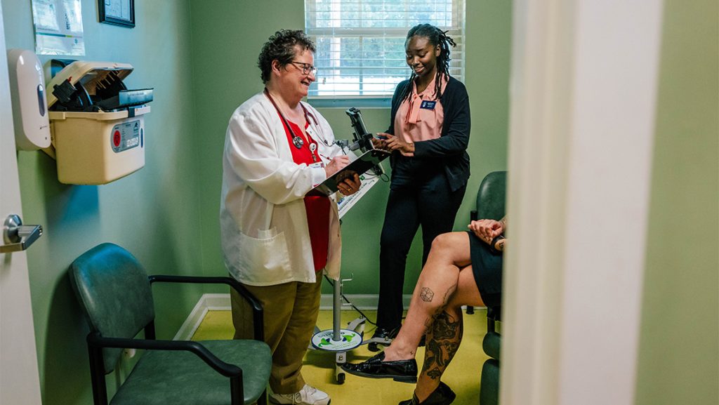 A medical practitioner and a student talk in an assessment room.