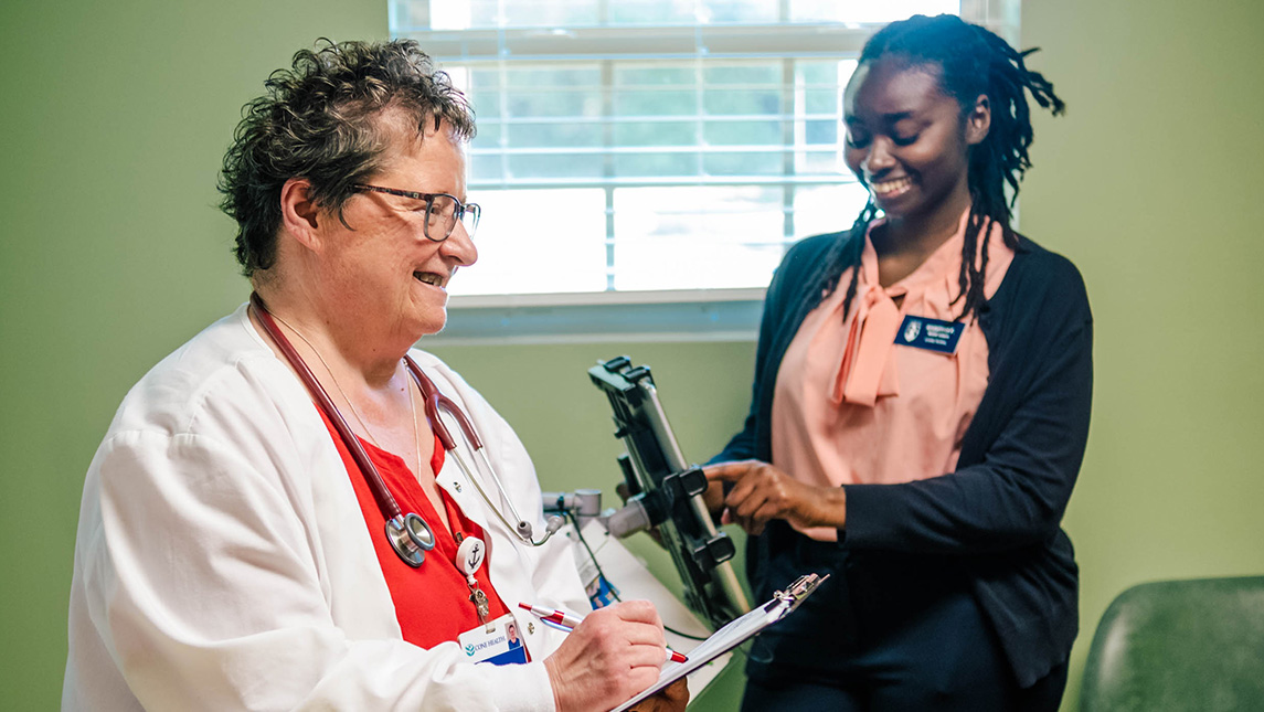 A student works talks to a medical practitioner in an assessment room.