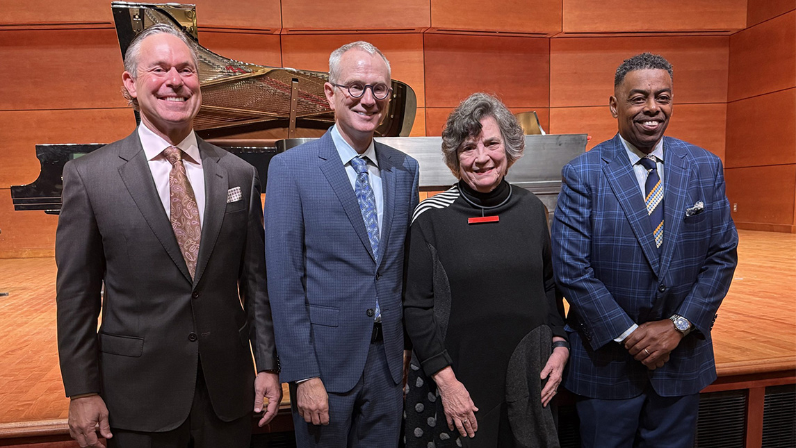 George Hoyle, UNCG Dean bruce mcclung, Connie Kotis, and Chancellor Gilliam stand in front of a stage with a piano.