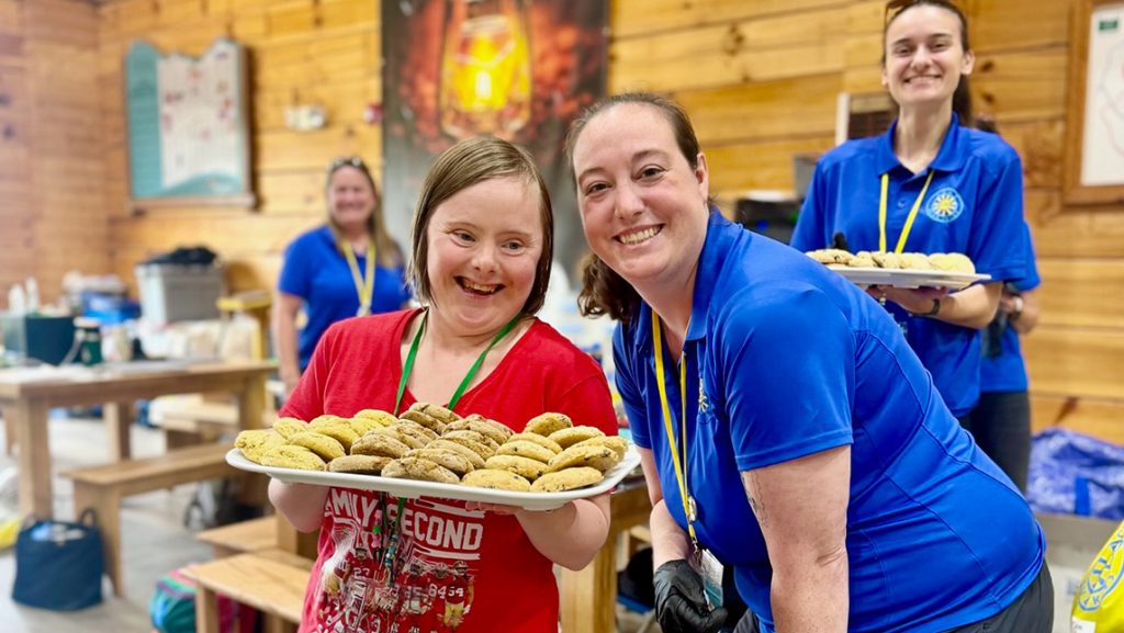 Kristin Bogner poses next to a woman holding a tray of cookies.