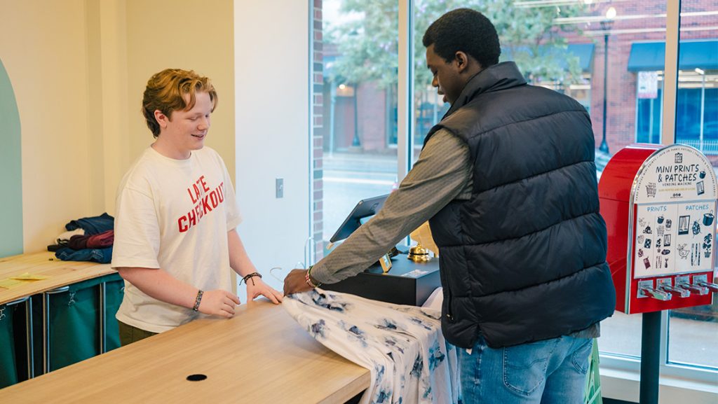 A cashier rings up a clothing purchase for a man.