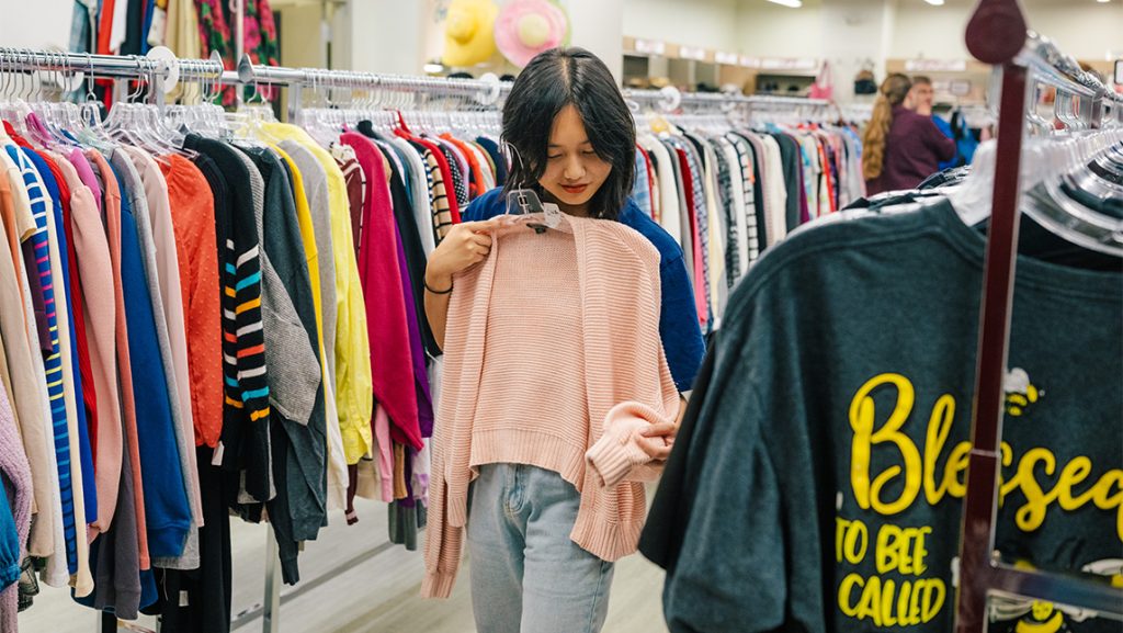A woman checks the size of a sweater on a hanger.