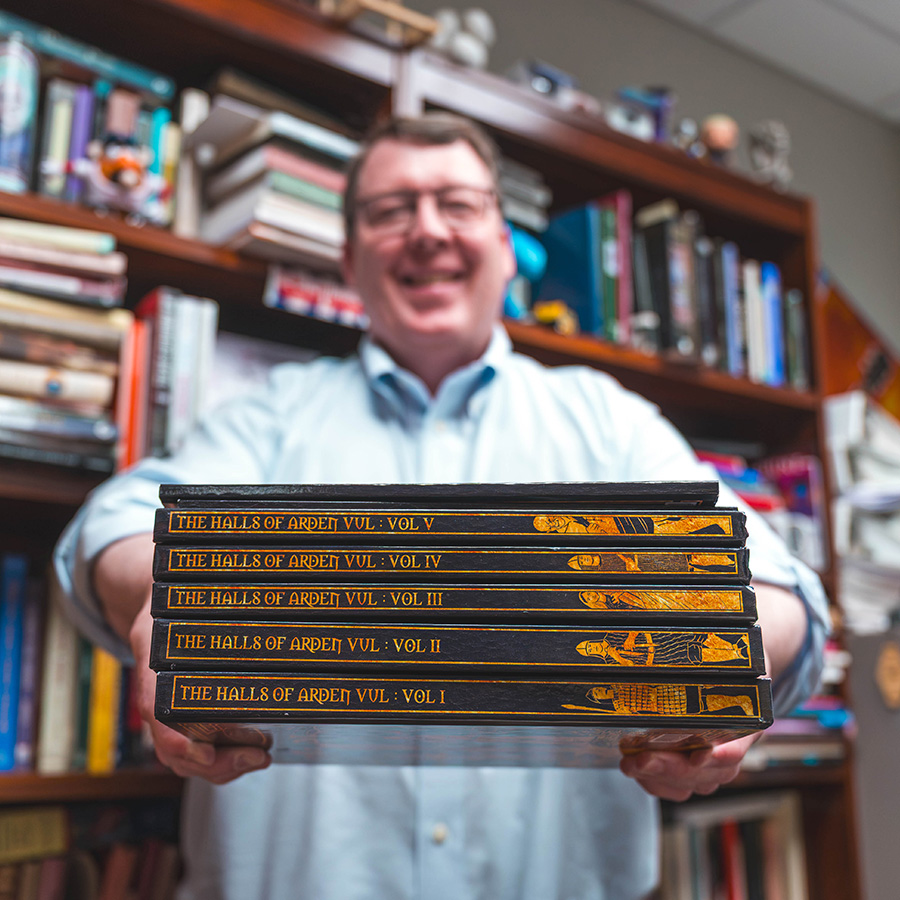 Dr. Rick Barton holds up his books The Halls of Arden Vul.